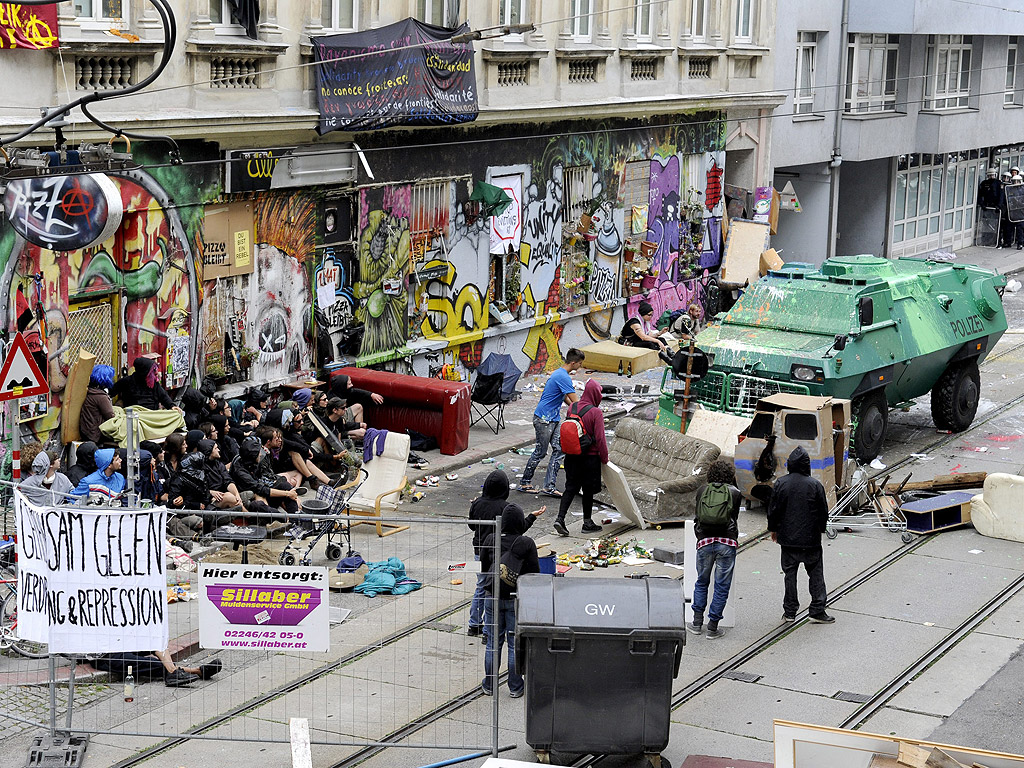 Брониран полицейски автомобил разчиства барикади пред къща обитавана от незаконно настанили във Виена, Австрия.