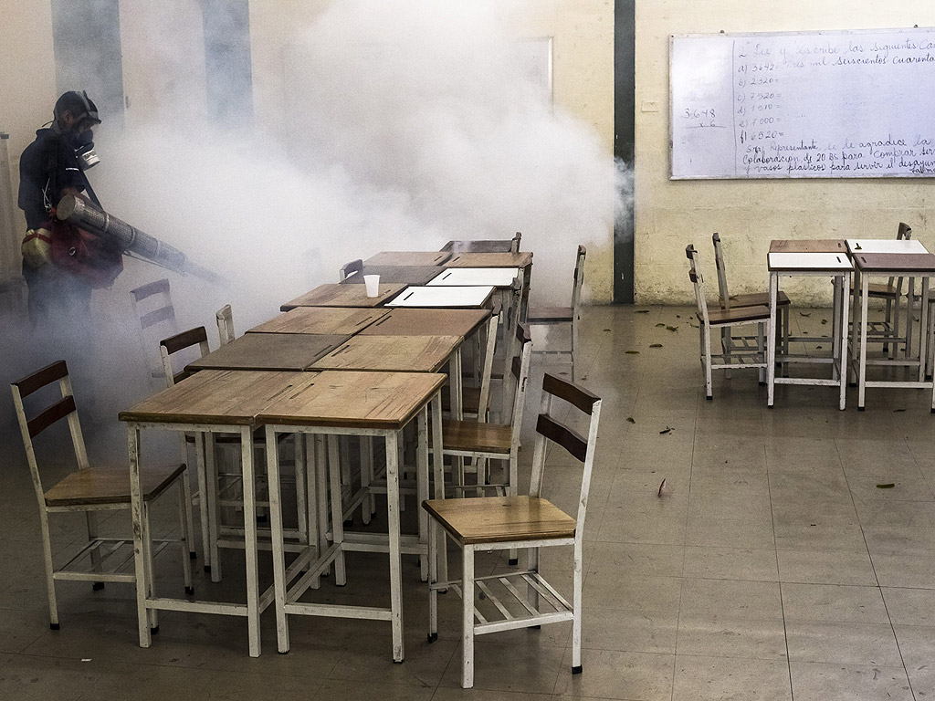 Работници дезинфектират училище срещу комари в квартал Първи Май, в Каракас, Венецуела. Правителство работи в кампания за контрол на вируса Чикунгуня и тропическата треска, които са заразили повече от 50 000 души в страната