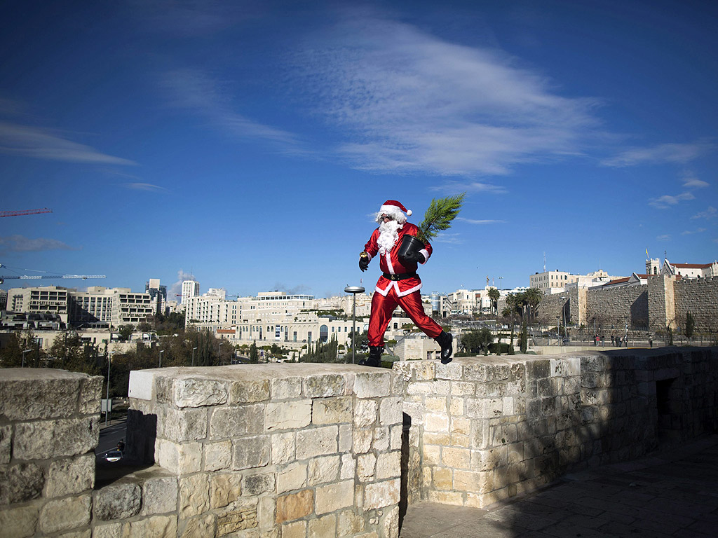 Палестинец, облечен в костюм на Дядо Коледа крачи по стените на Стария град на Йерусалим, Израел