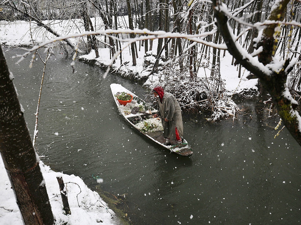 Кашмирски лодкар управлява лодка натоварена със зеленчуци по време на нов сняг в Шринагар, лятната столица на индийския щат Кашмир, който наруши нормалния ритъм на живота и затвори магистрала Шринагар-Джаму, единствената пътна връзка, свързваща област Кашмир с останалия свят.