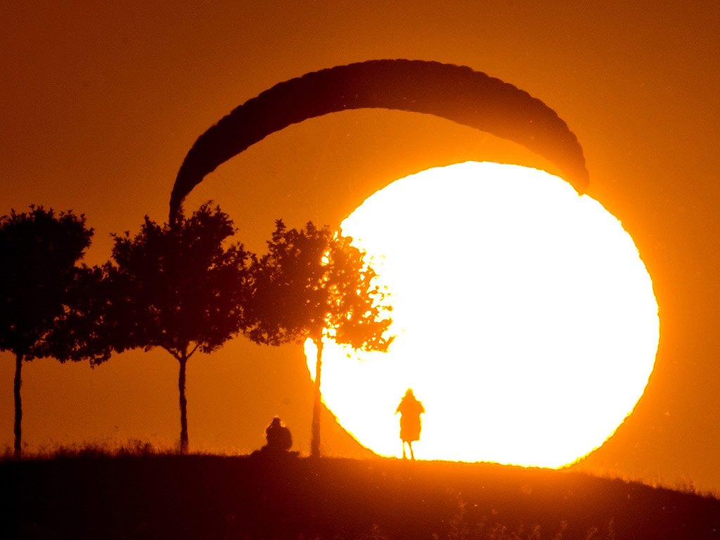 Парапланер се приземява при залез слънце в Kronsberg, Хановер, Германия