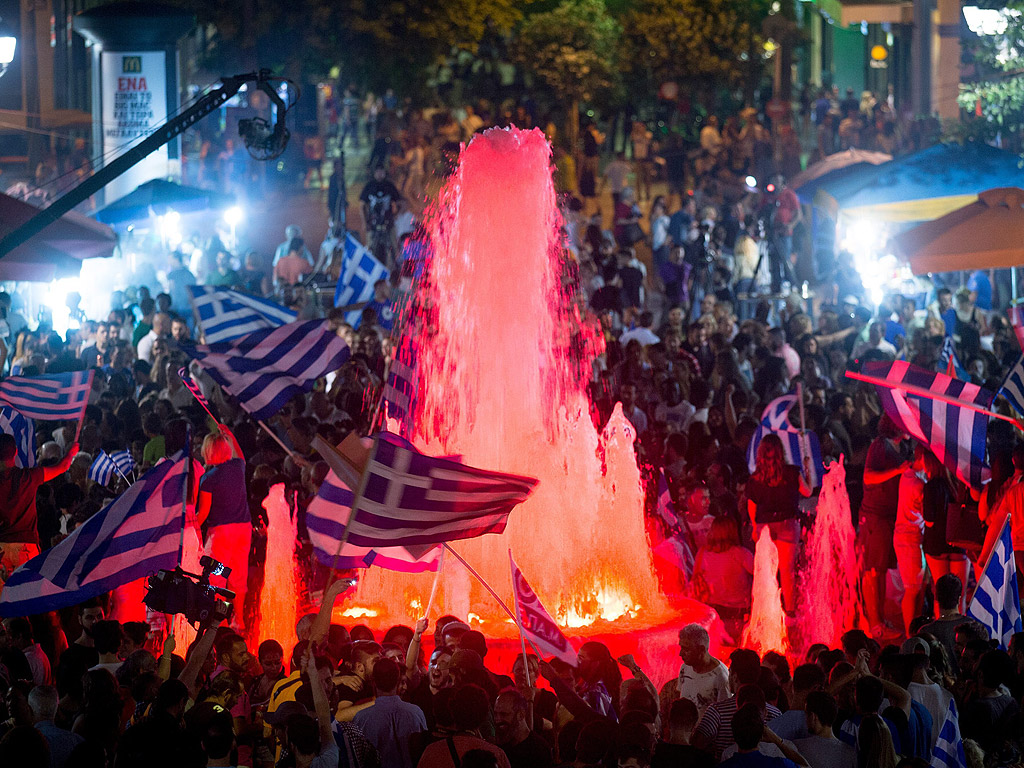 Привържениците на партията СИРИЗА и развяват знамена след резултатите от референдума пред гръцкия парламент в центъра на Атина, Гърция.
