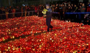 Полицай минава покрай килим от свещи пред клуба, в който загинаха 32 души в петък вечерта