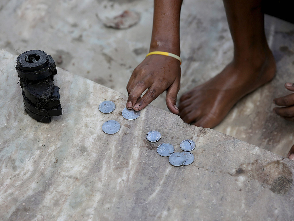 Индийско момче събира монети от замърсената река Ади Ганга до храма Калигхат в Калкута, Източна Индия. Най-малко сто момчета печелят доходите си чрез събиране на монети, които са били хвърлени в реката като дар от вярващи. Те събират монети на стойност между 1 и 10 щатски долара на ден, което често е техен или на техните семейства единствен източник на доходи