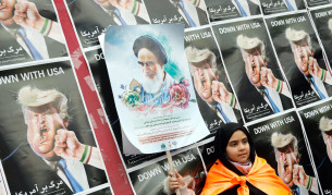 Момиченце държи постер на покойния основател на Ислямската република Аятолах Хомейни пред карикатури на Доналд Тръмп