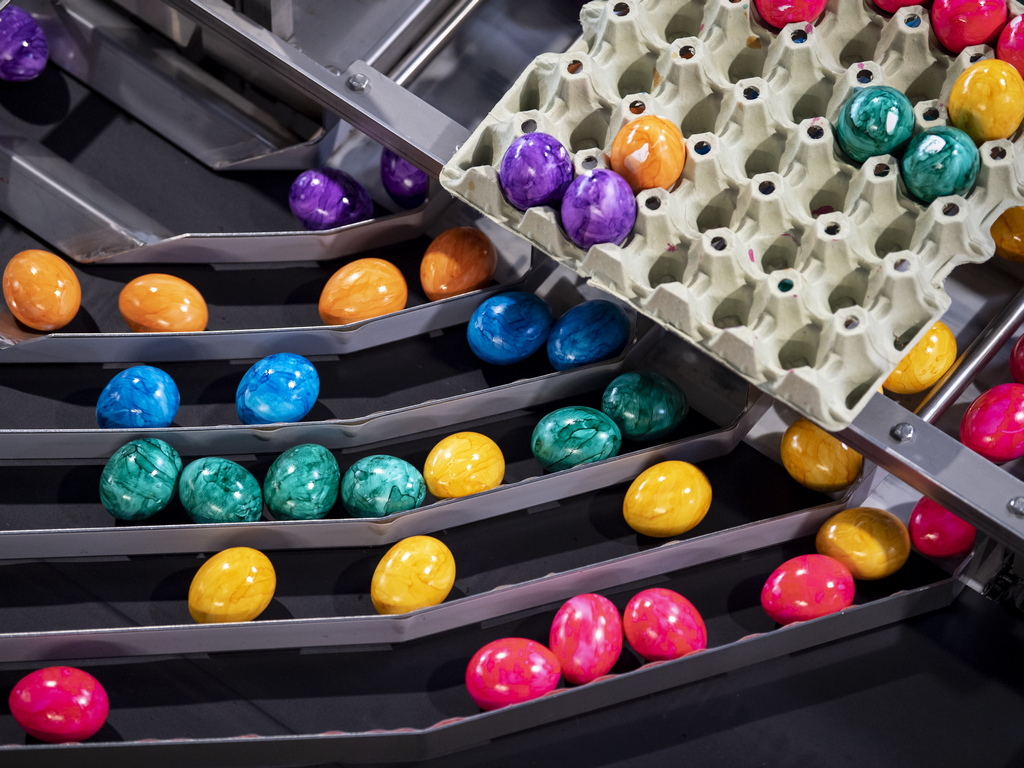 Яйца се движат по конвейерна лента за оцветяване в Танхаузен, Германия. Семейният бизнес е с капацитет до 250 000 яйца на ден в седмиците преди Великден. Яйцата, оцветени в шест различни цвята, се продават в Бавария, Баден-Вюртемберг, Австрия и Южен Тирол