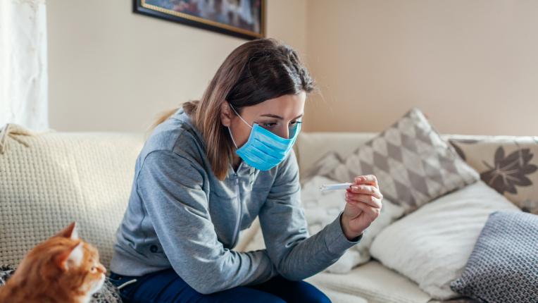 жена с маска срещу коронавирус у дома