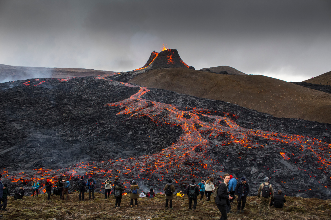 <p>Хора наблюдават и правят снимки, докато лава изтича след изригването на вулкана на полуостров Рейкянес в югозападната част на Исландия.</p>