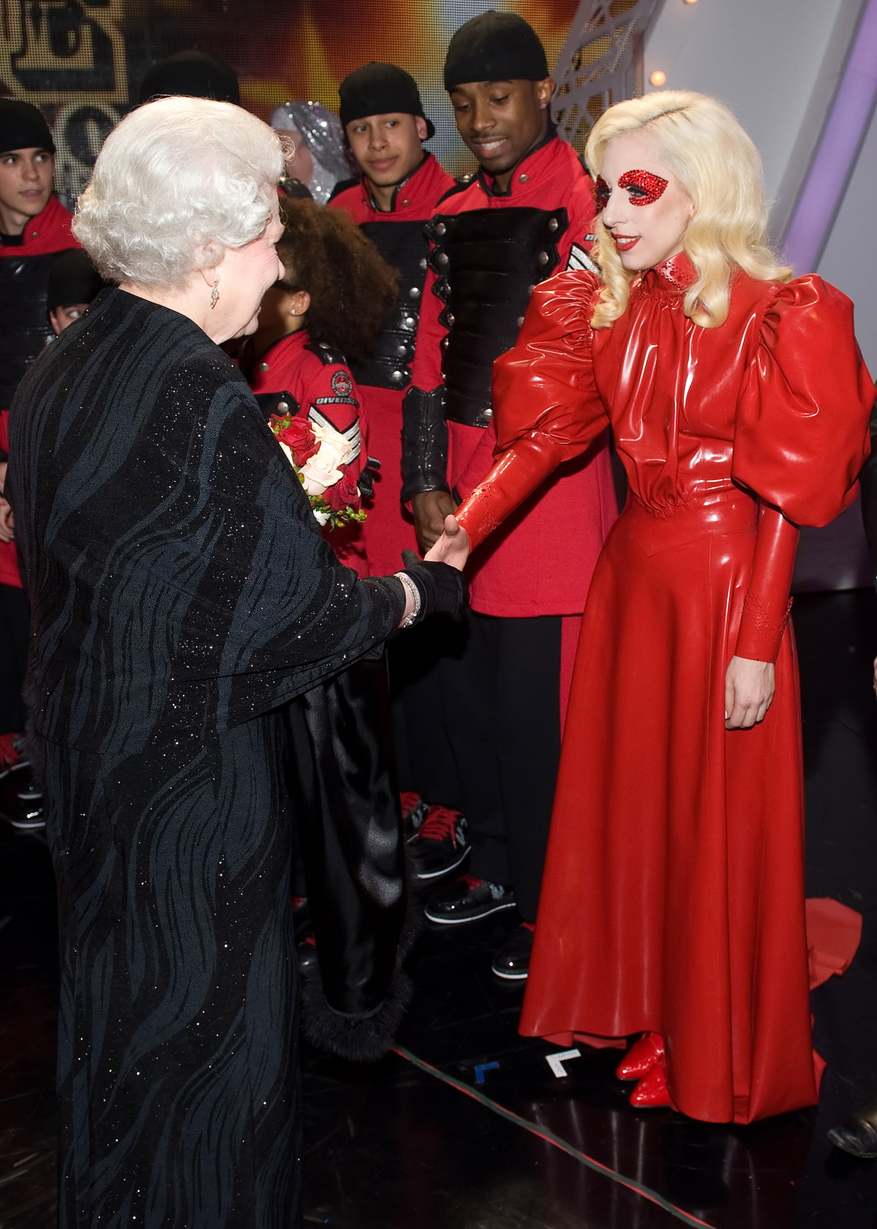 <p>Лейди Гага се среща с кралица Елизабет II в периода, известен с ексцентричните ѝ костюми. Тук тя носи червена латексова рокля и червена маска за очите.</p>