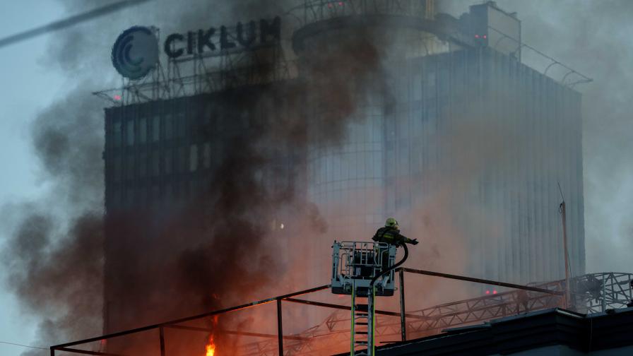 Огнеборец гаси пожар в офис сграда, поразена при руски удар с дронове в украинската столица Киев, 25 септември 2026 г.