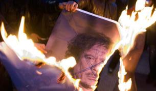 Докато светът се опитва да подходи възможно най-дипломатически, гражданите протестират палейки портрети на либийския лидер Муамар Кадафи. Снимката е заснета в Швейцария