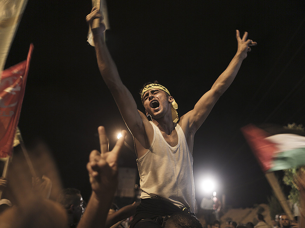 Палестинци издигат знамена на Фатах, докато чакат близо до границата между Израел и Ивицата Газа пристигането на освободени от израелски затвор палестински затворници.