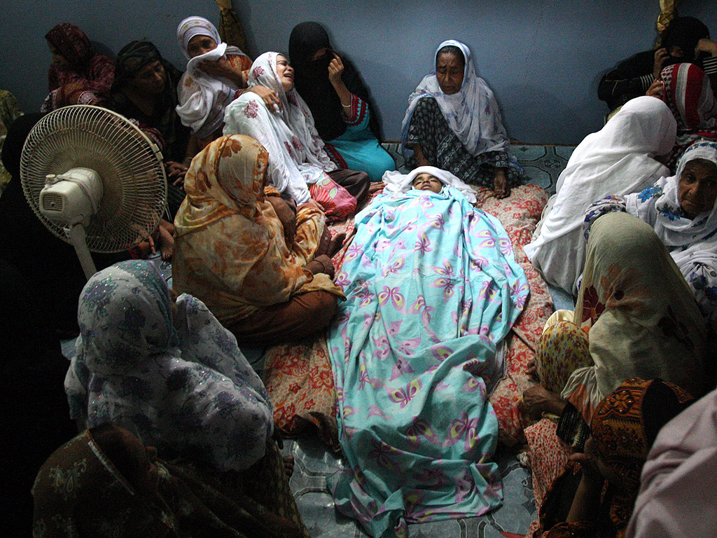 Близки на загинал при атентат в Карачи, Пакистан, на 7 август, стоят край тялото му. При атентата загинаха над 10 души.